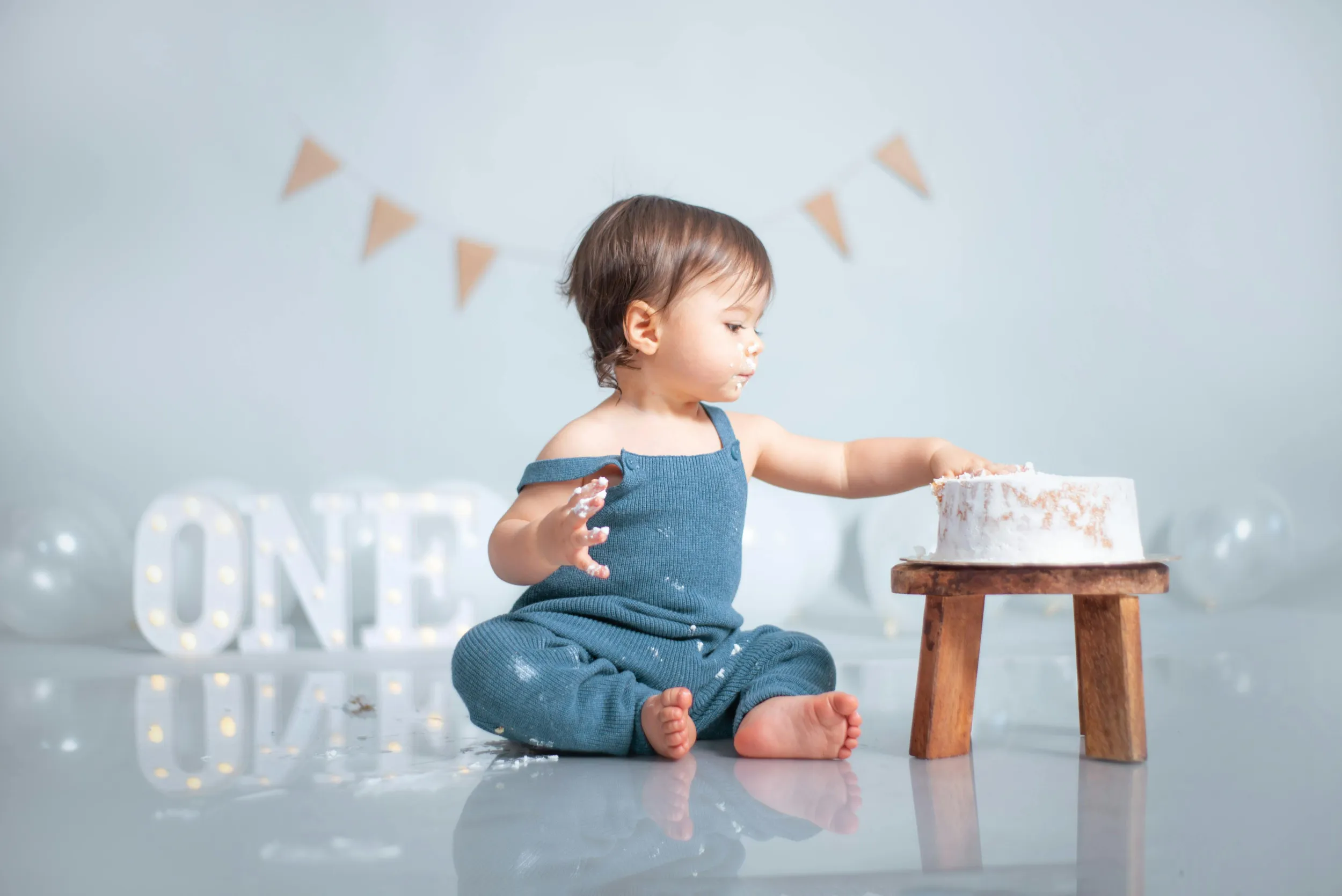 Baby zit naast een verjaardagstaart en viert eerste verjaardag