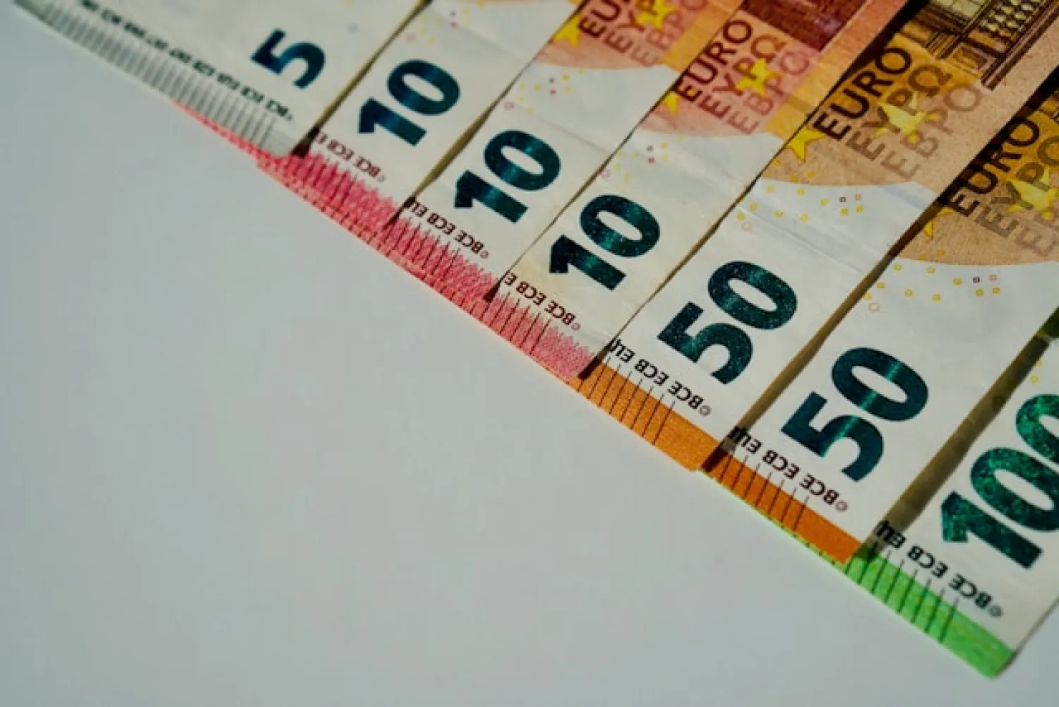 Een rij geldbiljetten oplopend van tien naar honderd euro op een tafel.