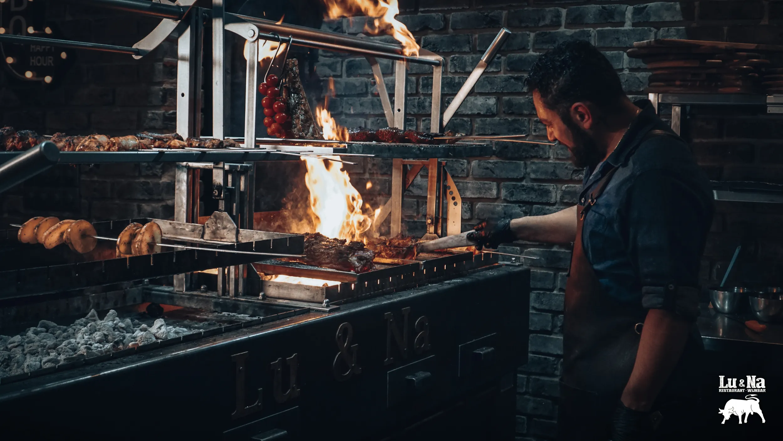 Man grilt vlees op een houtskoolgrill, met zichtbare vlammen.