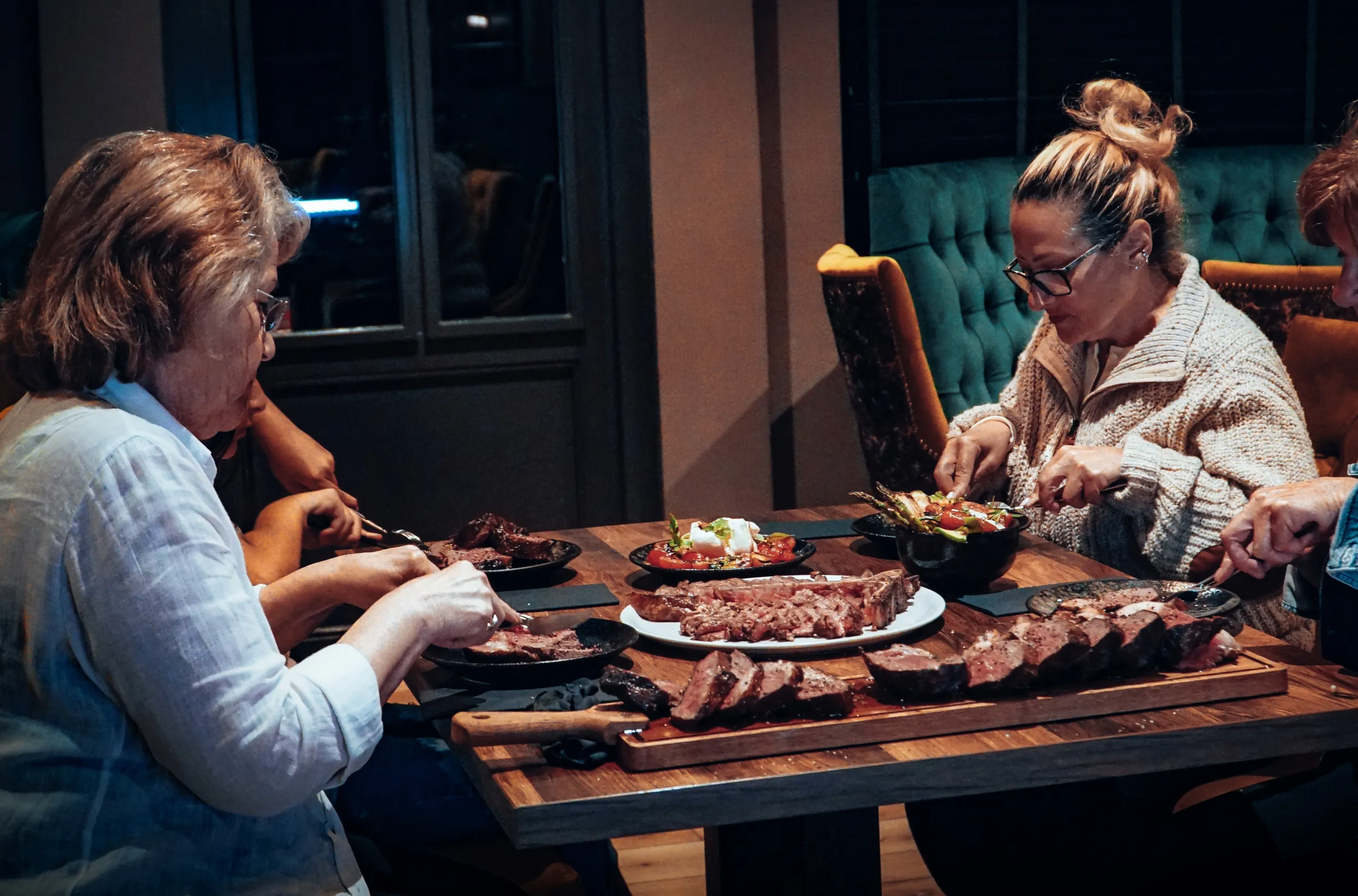 Vrouwen eten samen biefstuk aan tafel.