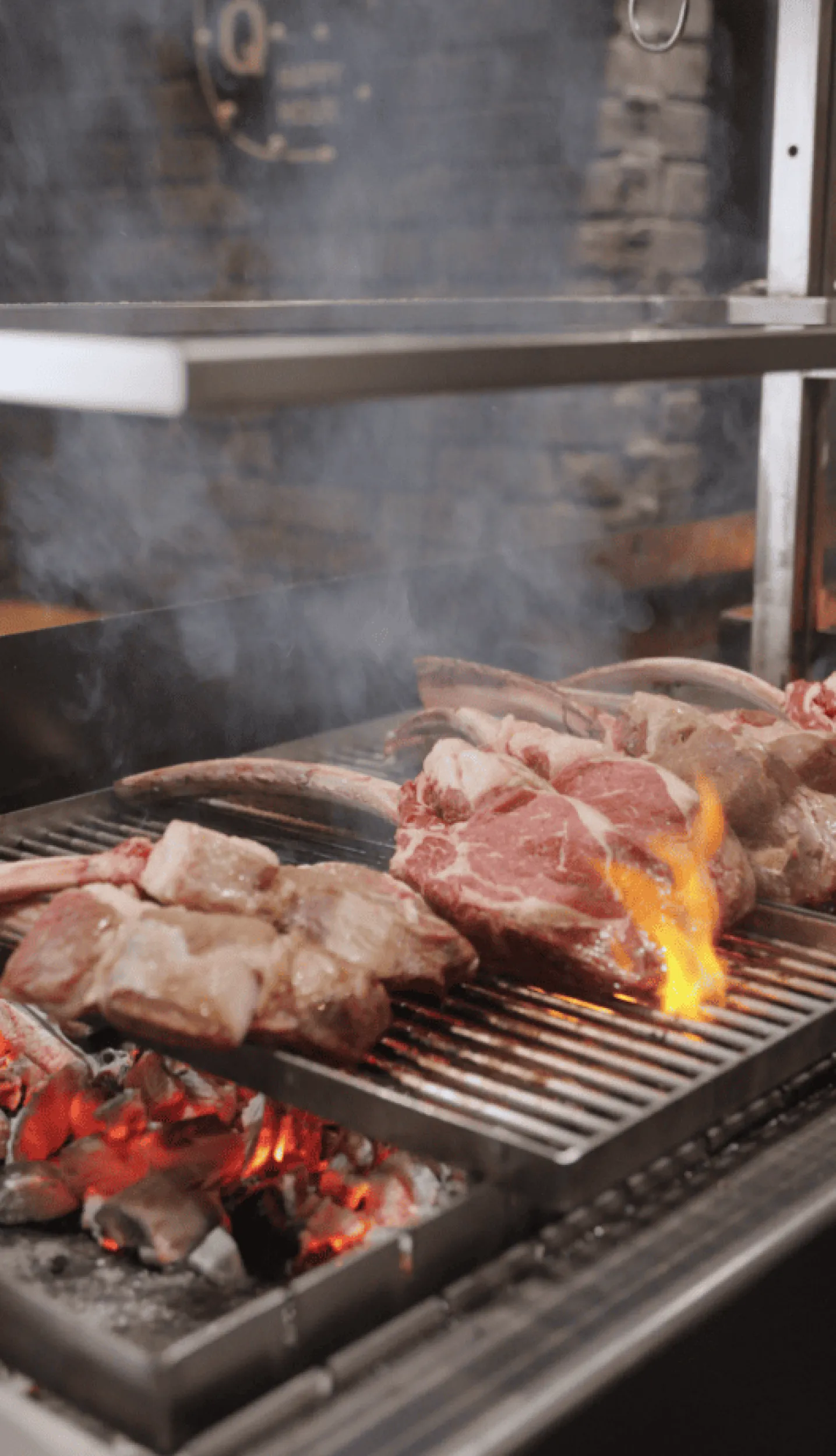 Stukken vlees naast elkaar op houtskool grill.