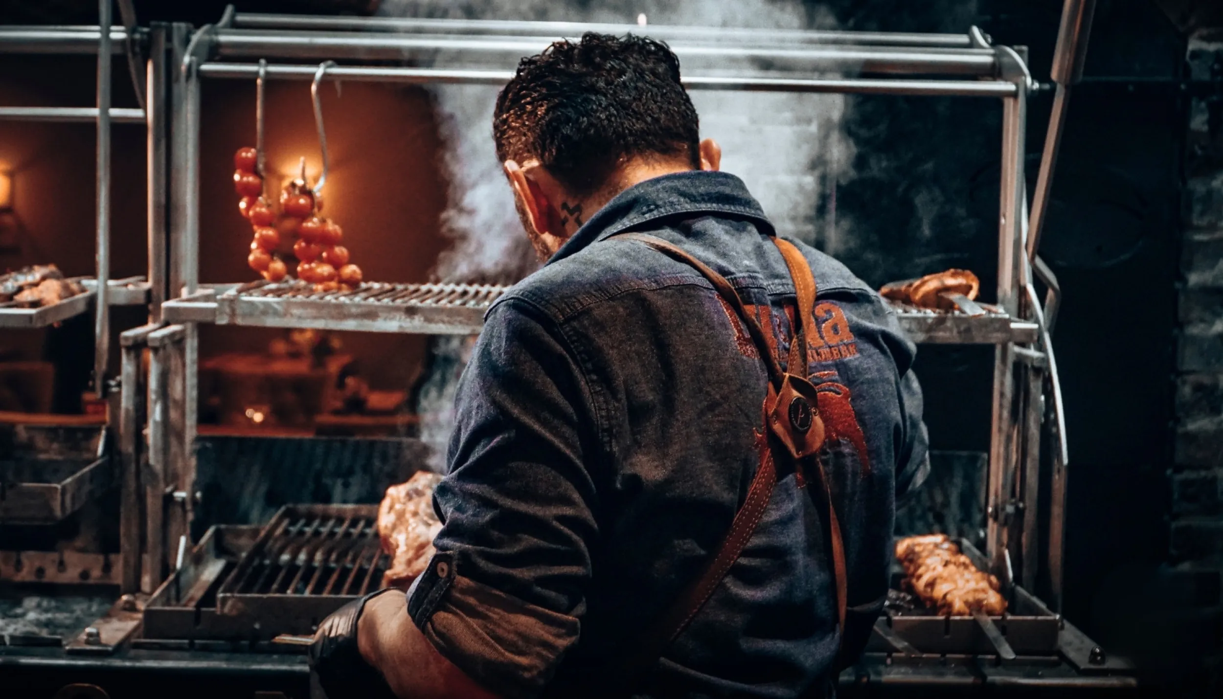 BBQ-chef staat bij een houtskoolgrill