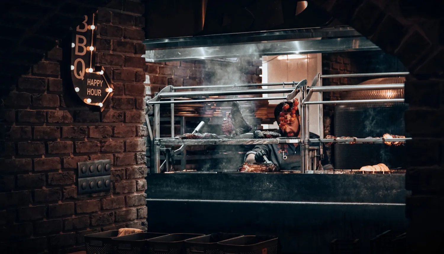 Man staat achter een houtskoolgrill in het restaurant