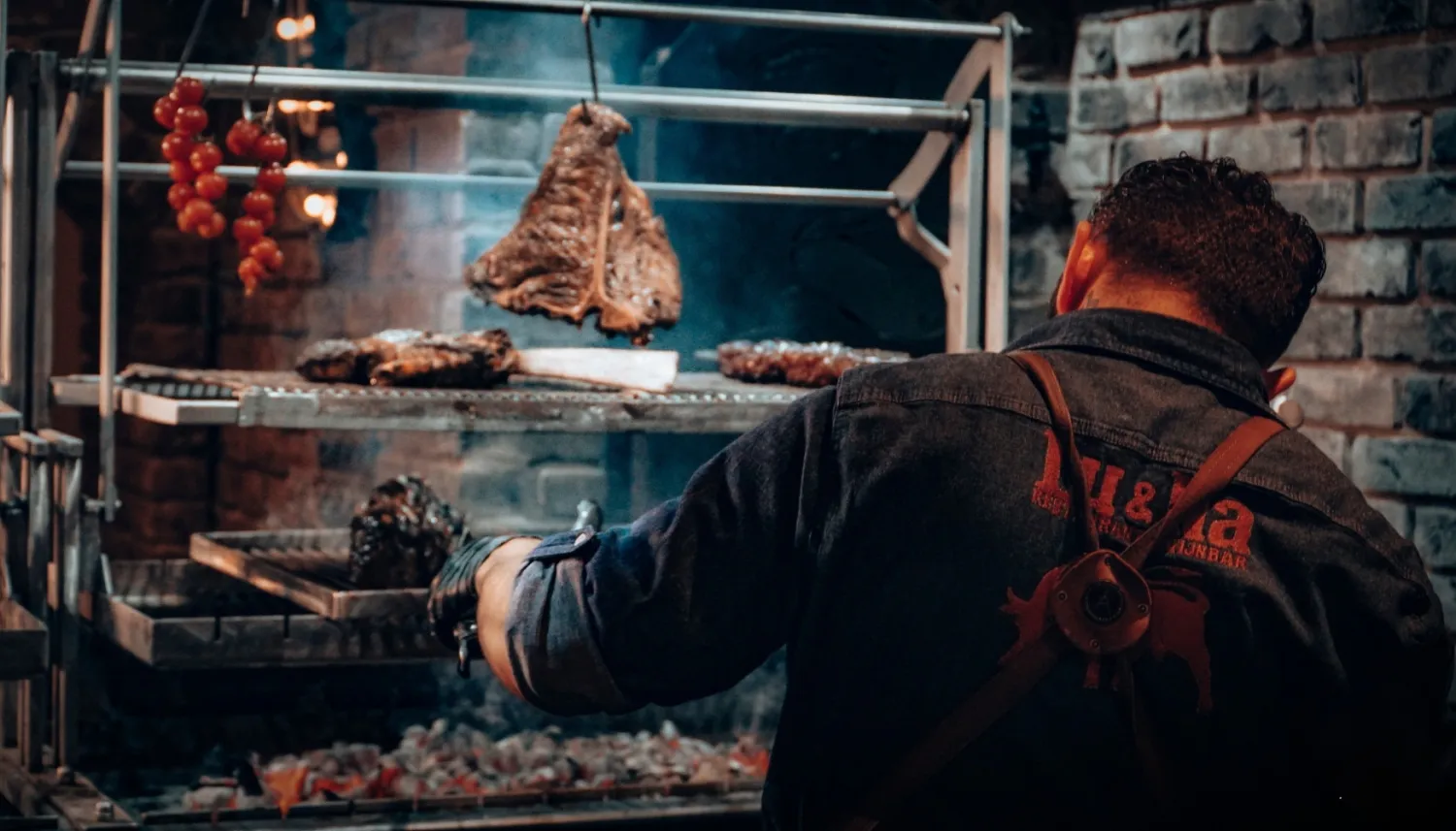 A man is cooking meat on the barbecue
