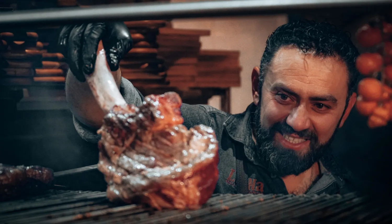 A man looks at grilled meat with a smile